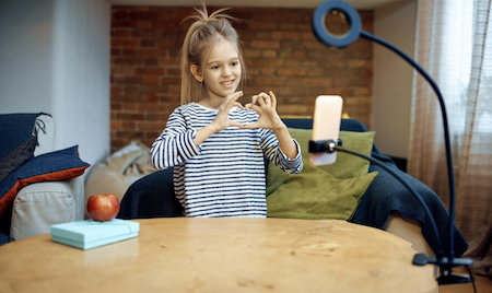 A kid signing what looks like a heart in front of the camera phone - Call Recording and Kids